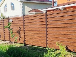 Горизонтальный забор из двухстороннего металлического штакетника под темное дерево в секциях с установкой
